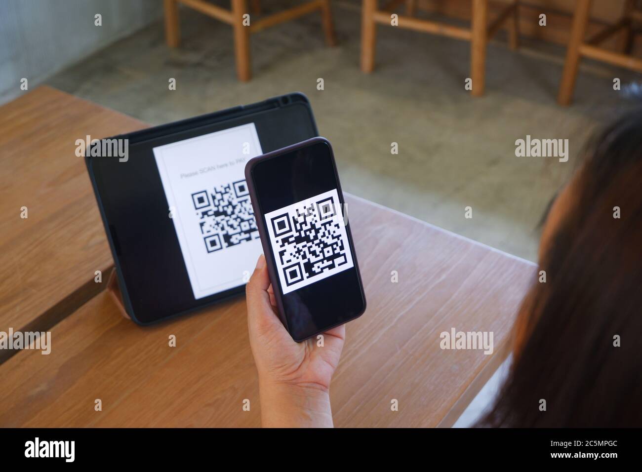 La main des femmes utilise une application de téléphone mobile pour scanner les codes QR dans les magasins qui acceptent les paiements numériques sans argent et les étiquettes en plastique sur la table. QR c Banque D'Images