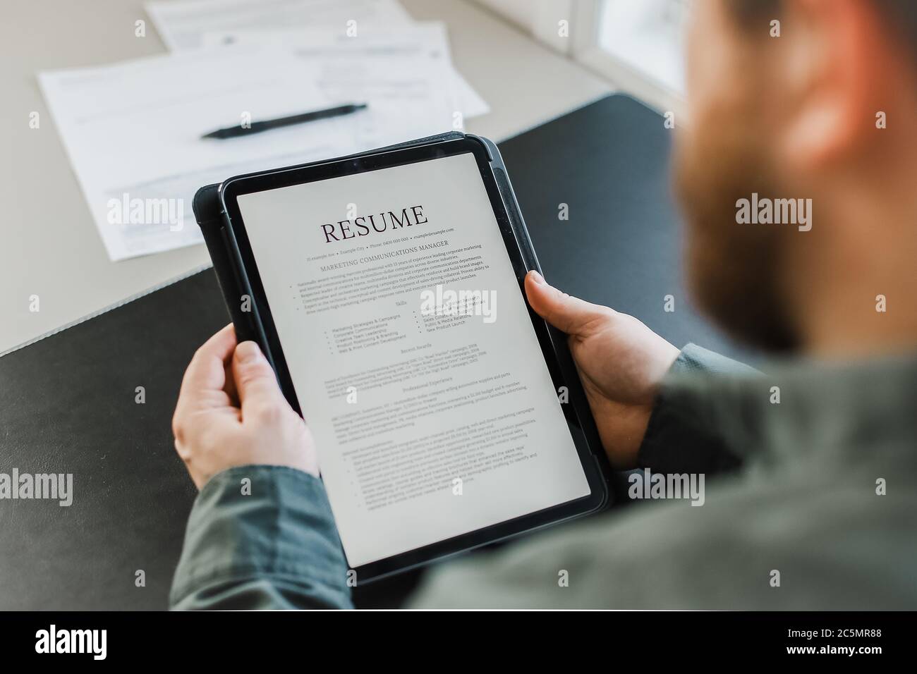 Le candidat à un emploi de sexe masculin examine le CV électronique sur une tablette. Banque D'Images