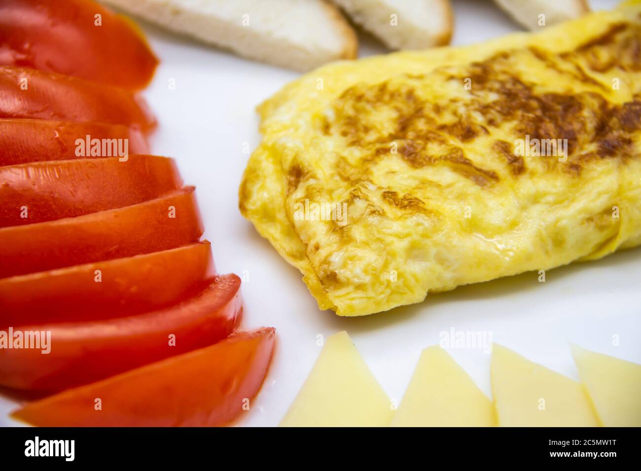 Petit déjeuner incroyable avec omelette savoureuse, tomates, fromage, pain et sauce sur la plaque blanche. Omelette délicieuse faite comme rolle, autres ingrédients. Savoureux Banque D'Images