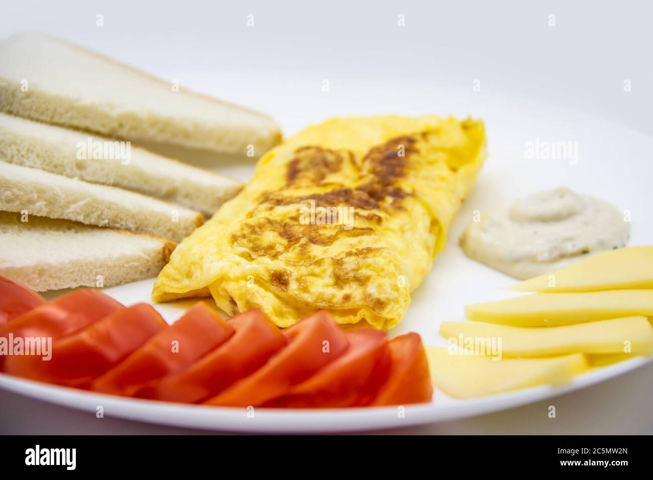 Petit déjeuner incroyable avec omelette savoureuse, tomates, fromage, pain et sauce sur la plaque blanche. Omelette délicieuse faite comme rolle, autres ingrédients. Savoureux Banque D'Images