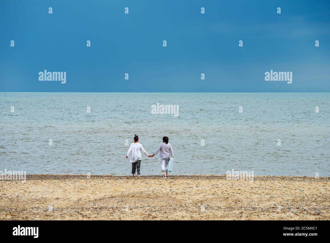 Southwold Suffolk Angleterre. Mère et fille marchant sur la plage. 1 juillet 2020 modèle sorti photo de mère et fille marchant vers la mer Banque D'Images
