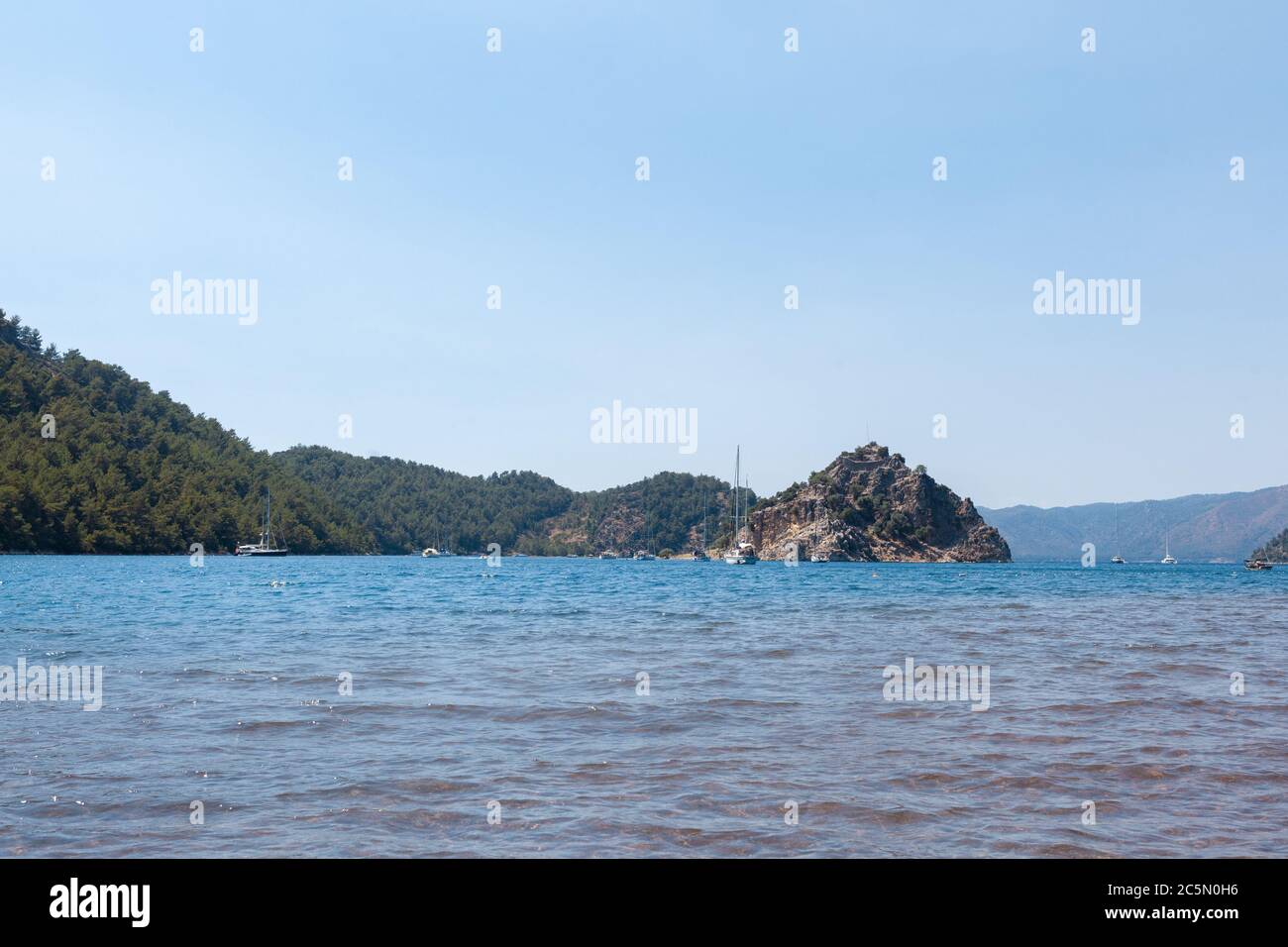 Une grande étendue d'eau avec des bateaux et une colline couverte d'arbres Banque D'Images