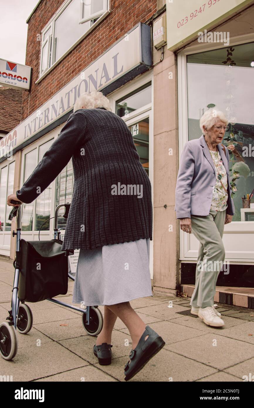 deux femmes âgées marchant les unes après les autres dans la rue, une des femmes utilise un cadre zimmer ou une aide à la mobilité Banque D'Images