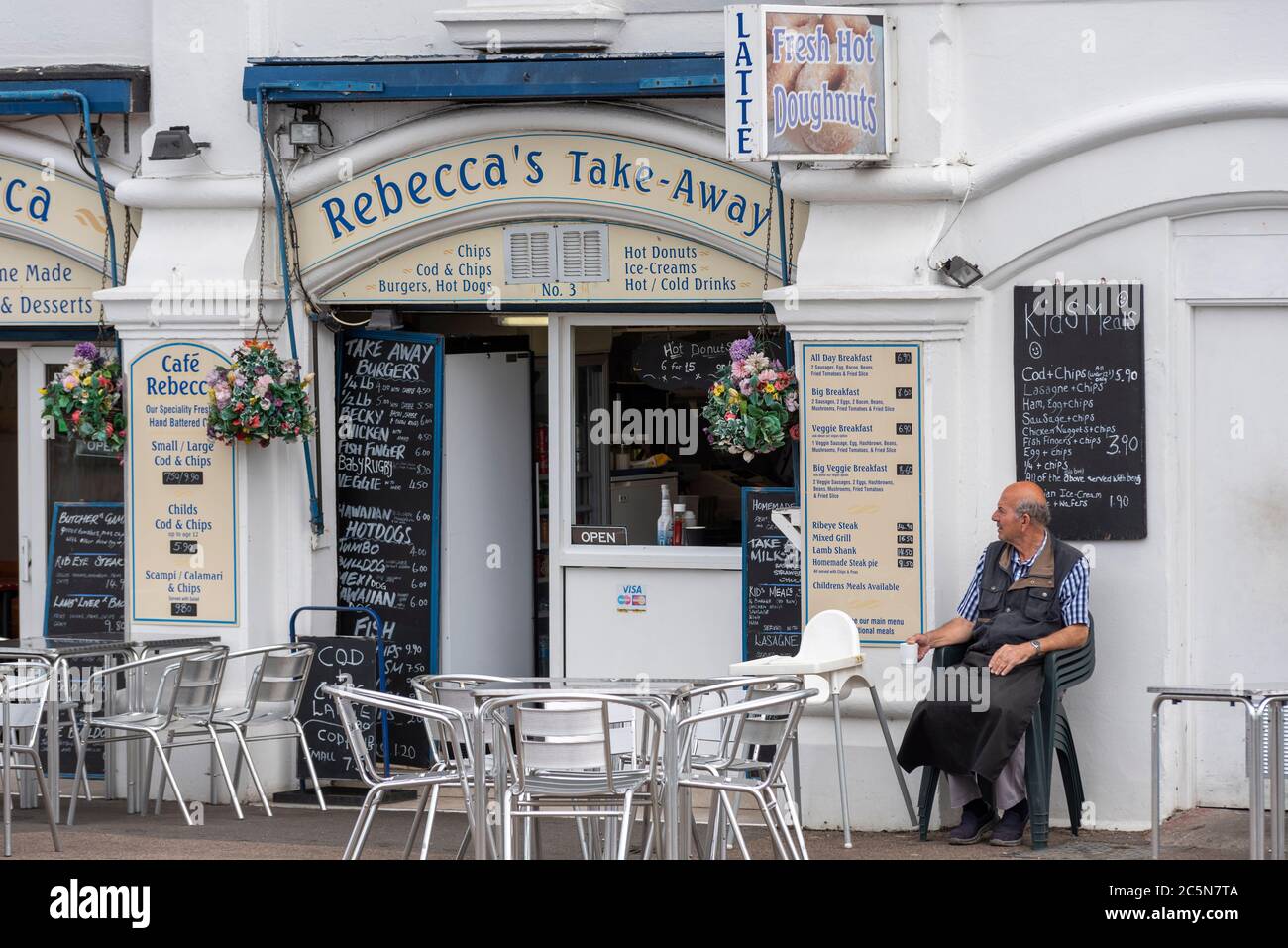 Southend on Sea, Essex, Royaume-Uni. 4 juillet 2020. Les pubs, restaurants et autres entreprises en Angleterre sont libres d'ouvrir leurs portes aux clients pour la première fois depuis le verrouillage du coronavirus COVID-19. Le gouvernement leur permet d'ouvrir à partir de 6h du matin comme facilité de verrouillage des mesures. À Southend on Sea, les arcades d'amusement en bord de mer et le parc à thème Adventure Island ont ouvert, bien que le temps froid venteux garde beaucoup de gens à l'écart. Aucun client pour ce café, avec un travailleur de sexe masculin assis en attendant pour affaires Banque D'Images