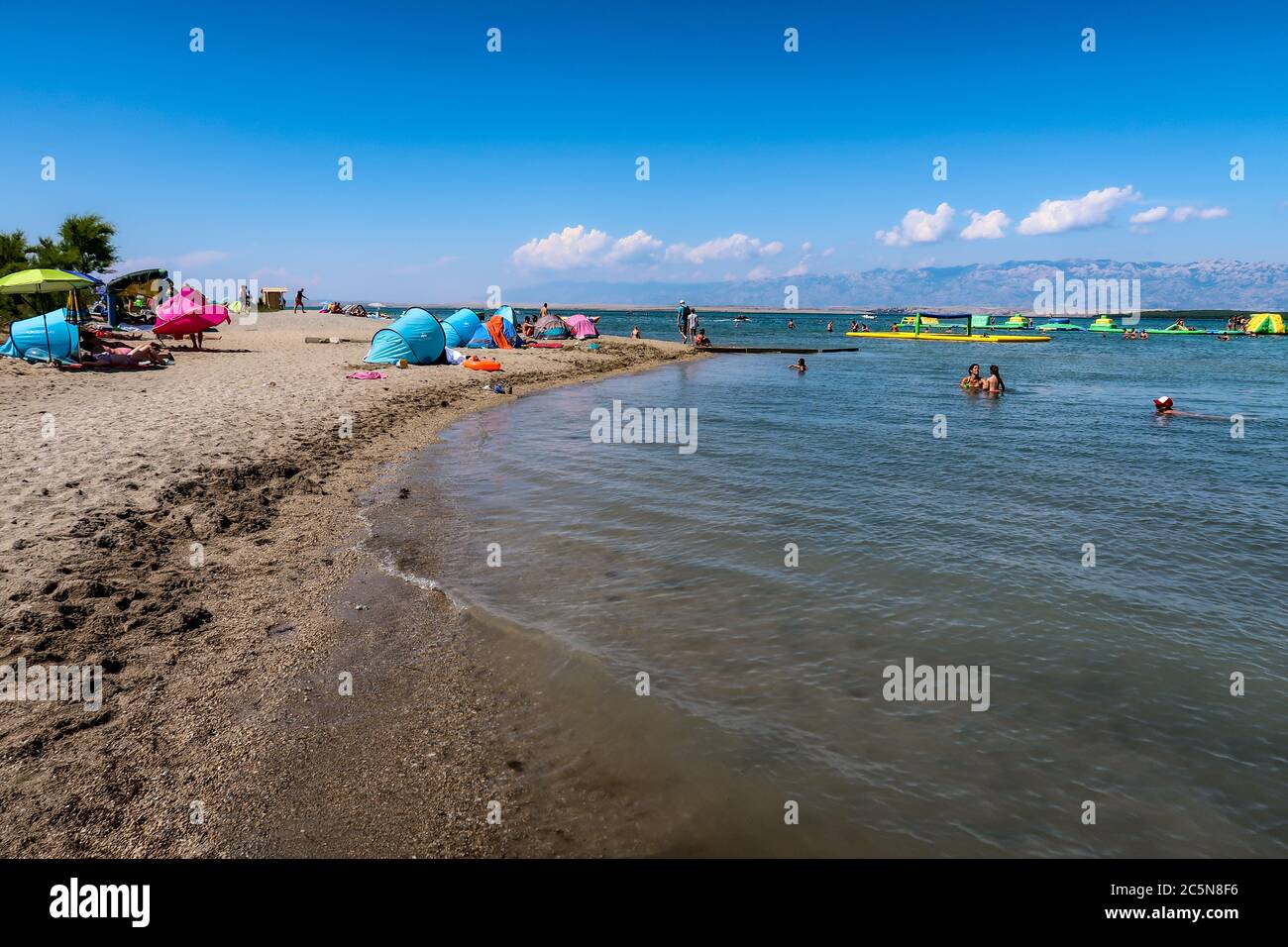 Plage de sable avec abris de soleil et parc aquatique au loin. Plage de Queen's, Nin, comté de Zadar, Dalmatie, Croatie Banque D'Images