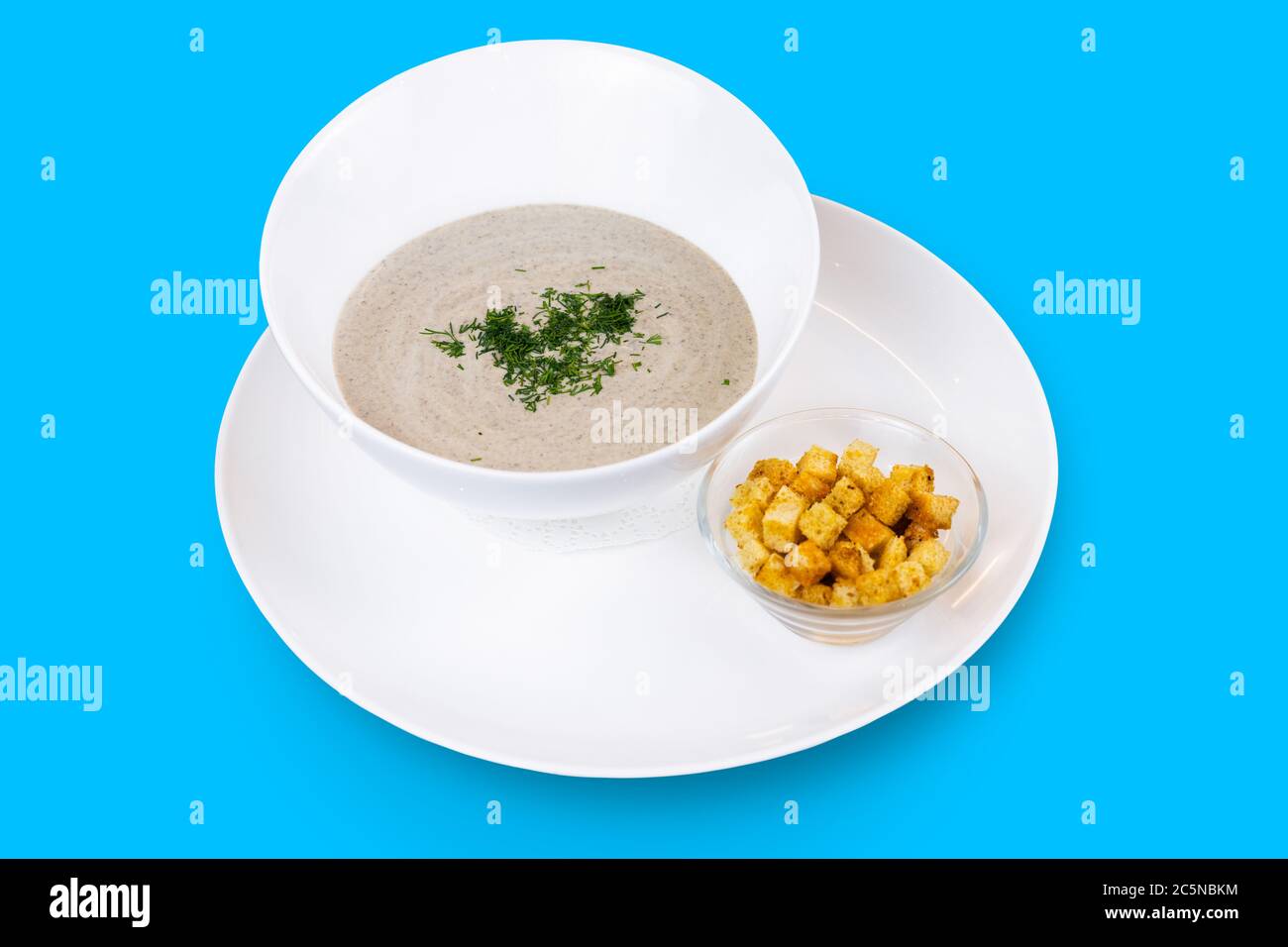 Soupe à la crème de champignons aux herbes et aux croûtons isolés sur fond bleu Banque D'Images