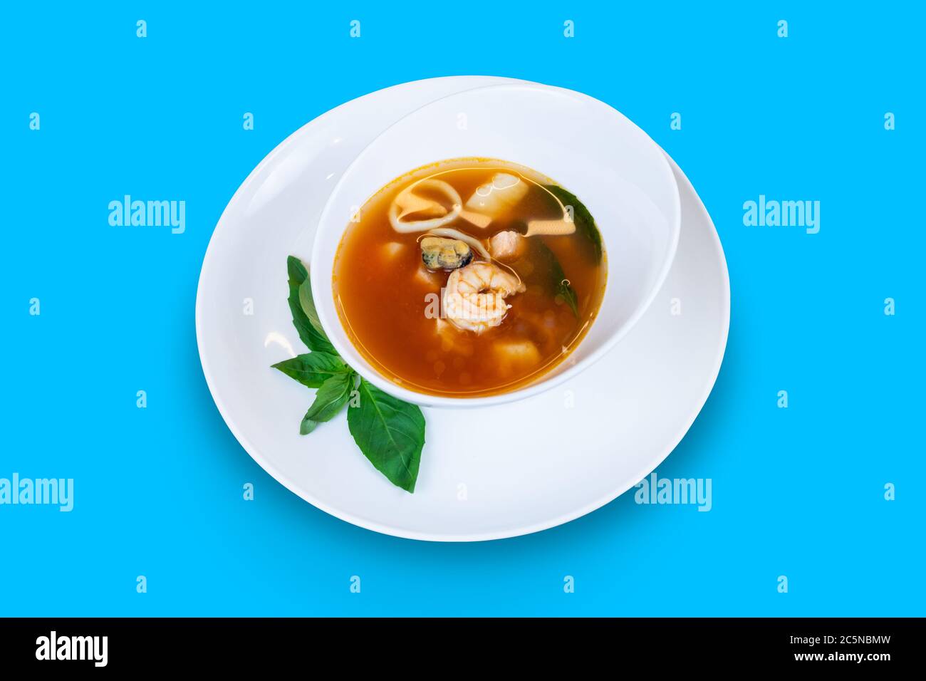Soupe de poisson avec saumon, calmar, crevettes, moules et pétoncles isolée sur fond bleu Banque D'Images