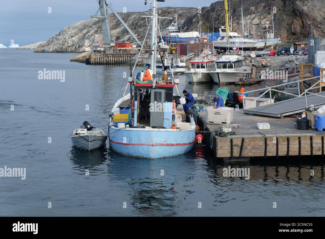 Les pêcheurs déchargeant les prises du petit chalutier bleu à Ilulissat hatbour. Banque D'Images