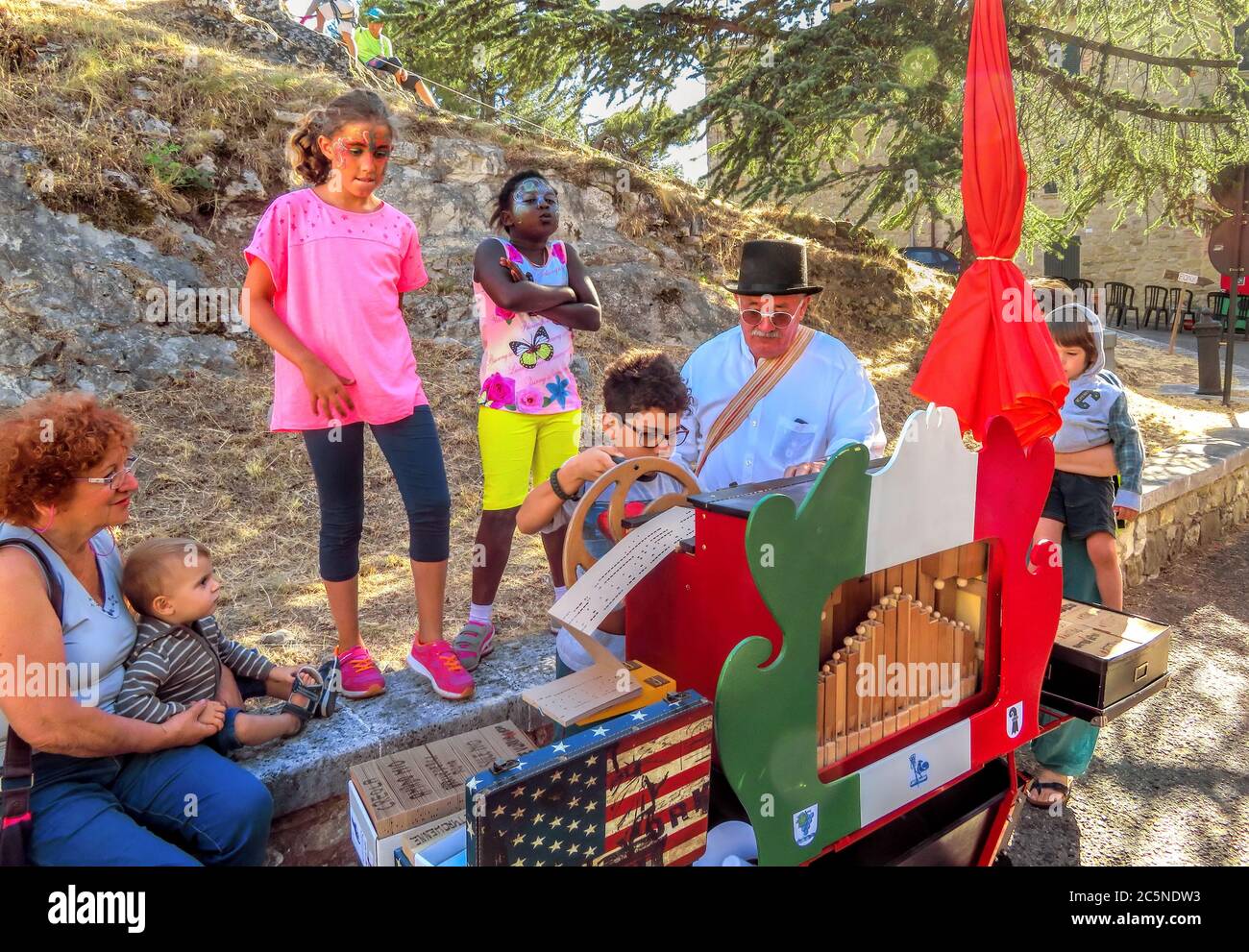 San Leo, Italie - 18 juin 2017 : un ancien musicien non identifié avec sur un orgue de canon enseigne aux enfants leur métier. Banque D'Images