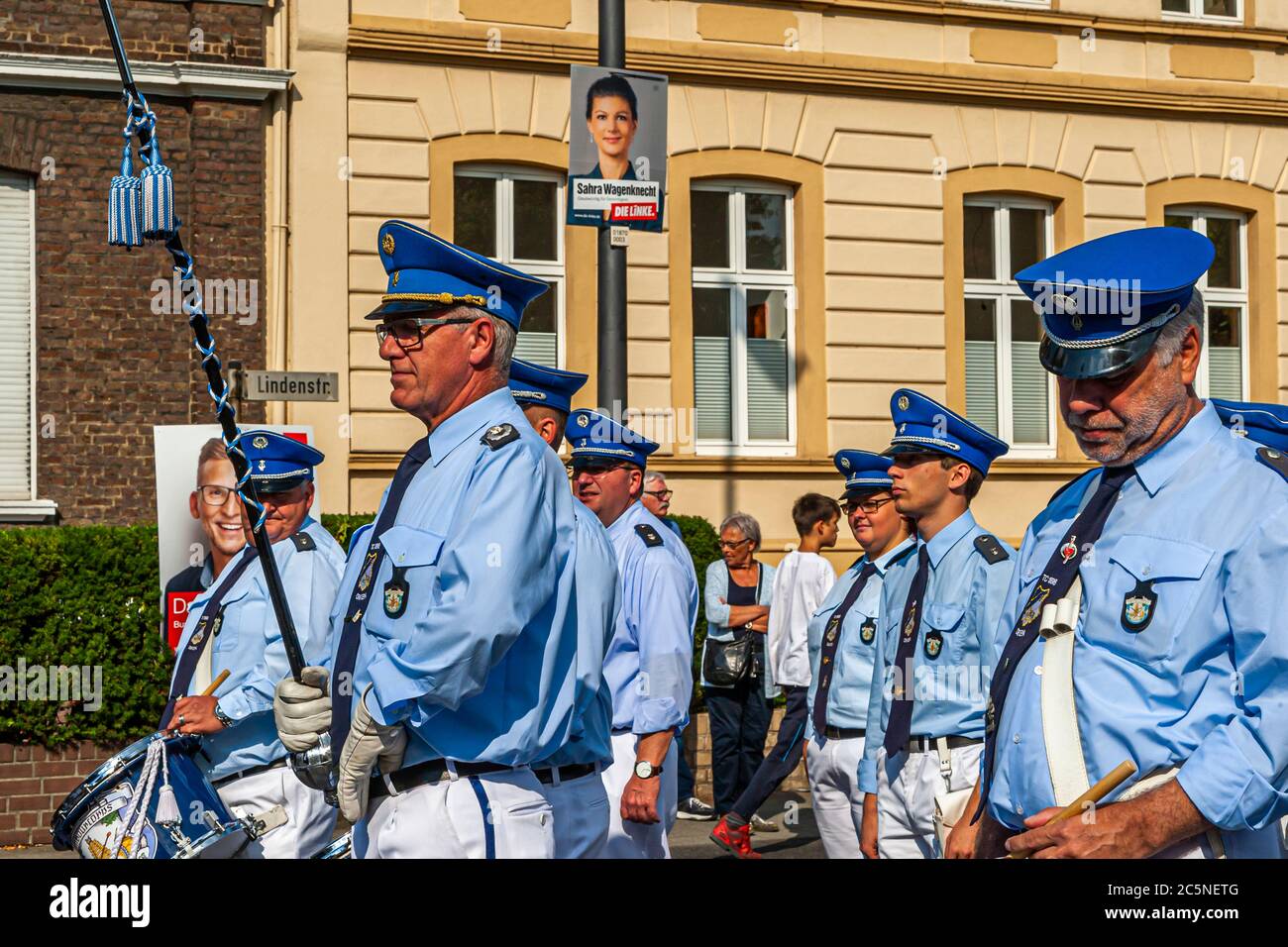 Affiche électorale avec le candidat supérieur du parti de gauche, Sahra Wagenknecht devant lequel les participants en uniforme d'une marche Schützenfest by. Funfair à Grevenbroich, Allemagne Banque D'Images