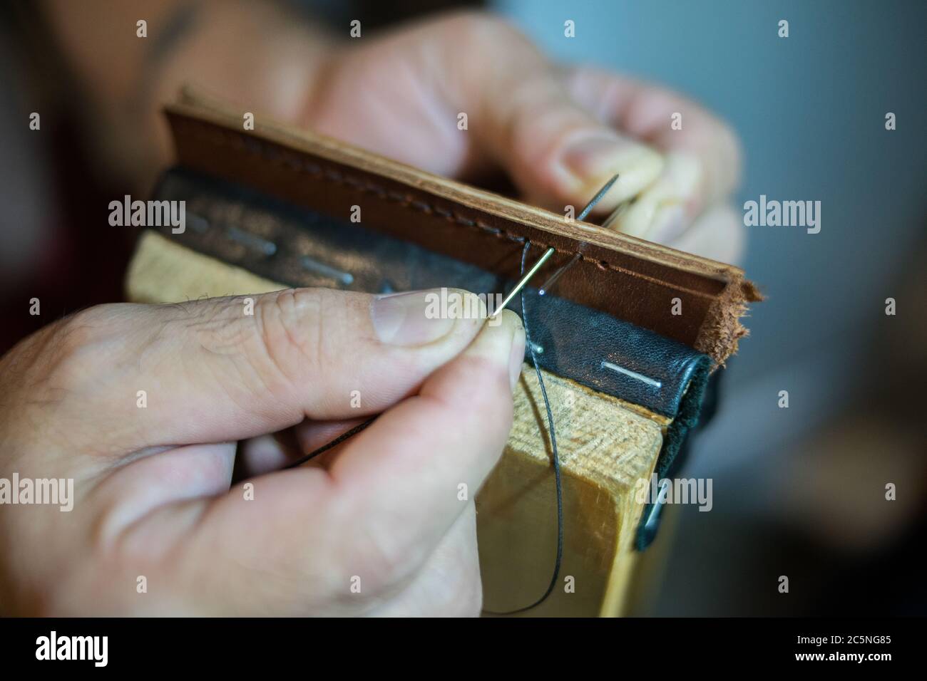 Les mains des hommes sont cousues grand en cuir avec une couture manuelle. Banque D'Images