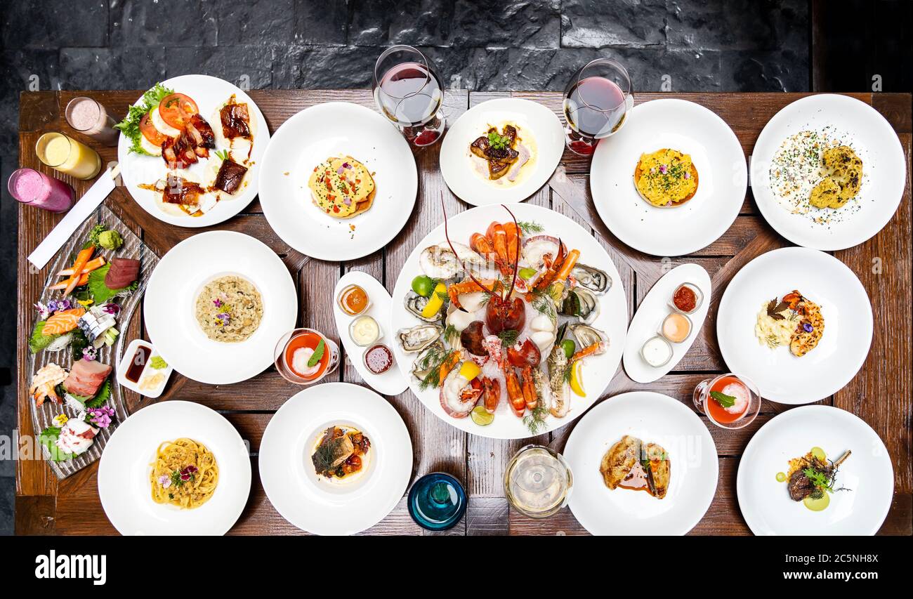 Vue sur le plan de table variété de plats internationaux de qualité dans le restaurant de crevettes de homard steak boeuf agneau pâtes spaghetti risotto riz sushi sashimi et wi Banque D'Images