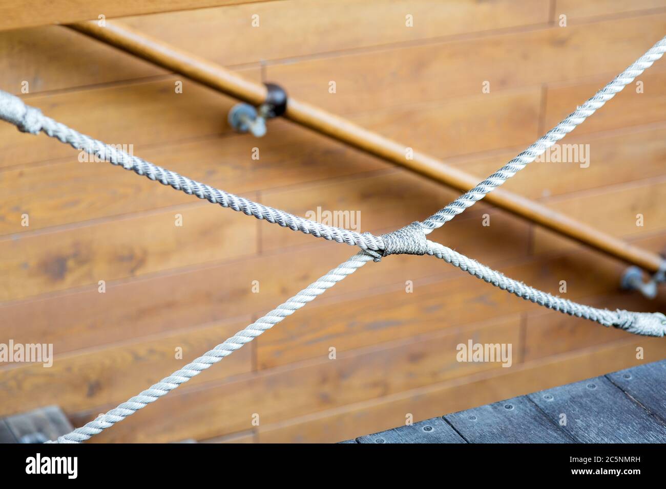 Corde décorative nouée, sur fond de planches de bokeh en bois avec une main courante sur la descente. Banque D'Images