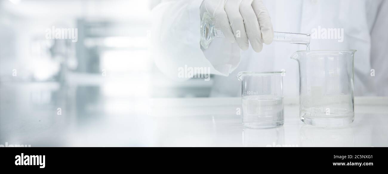 scientifique en couche blanche, portant de l'eau dans un bécher en verre dans un laboratoire médical, science bannière arrière-plan Banque D'Images