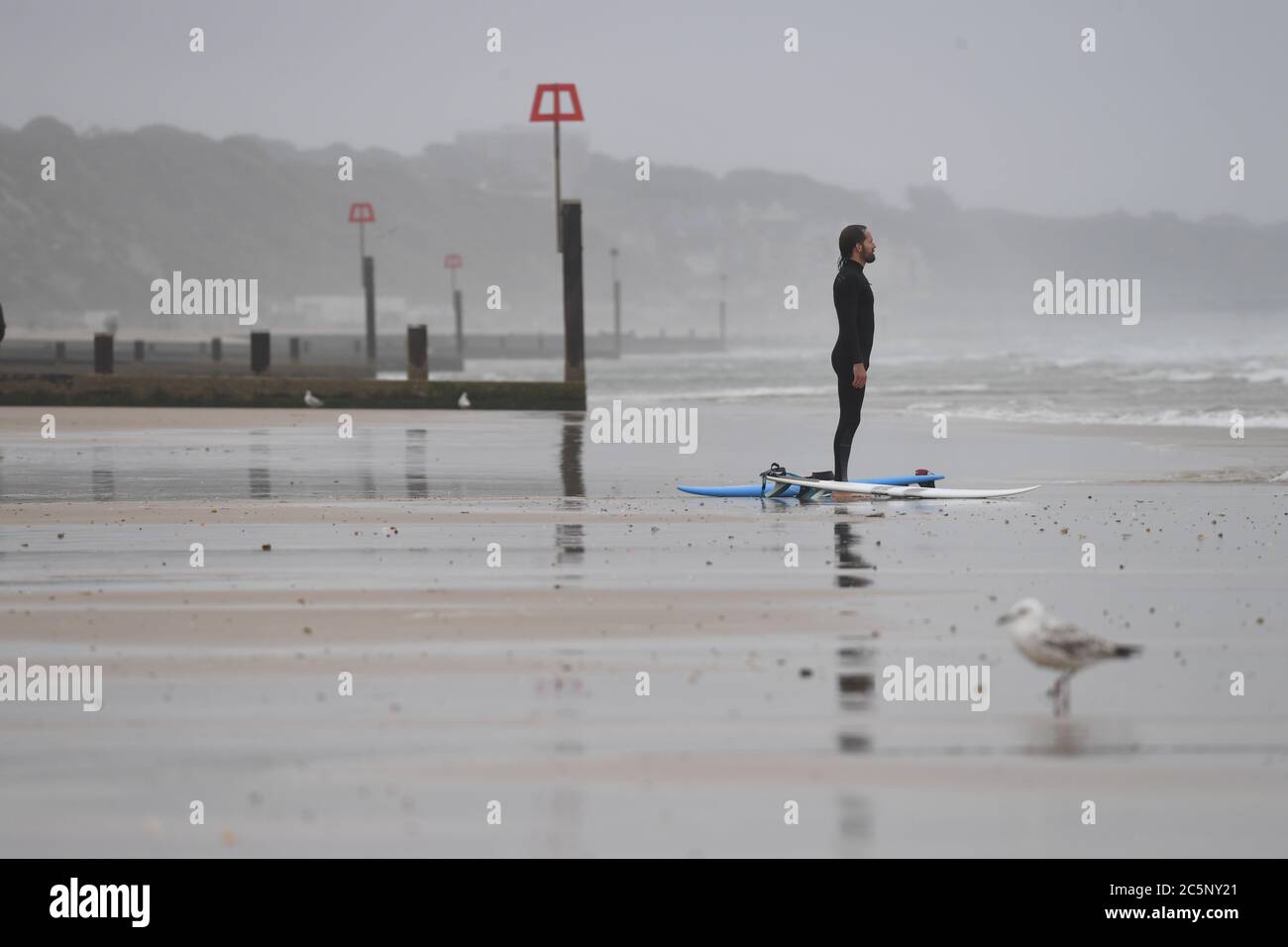 Surfeur sur la plage de Bournemouth malgré la pluie et la bruine que l'on attend dans une grande partie du pays. Banque D'Images
