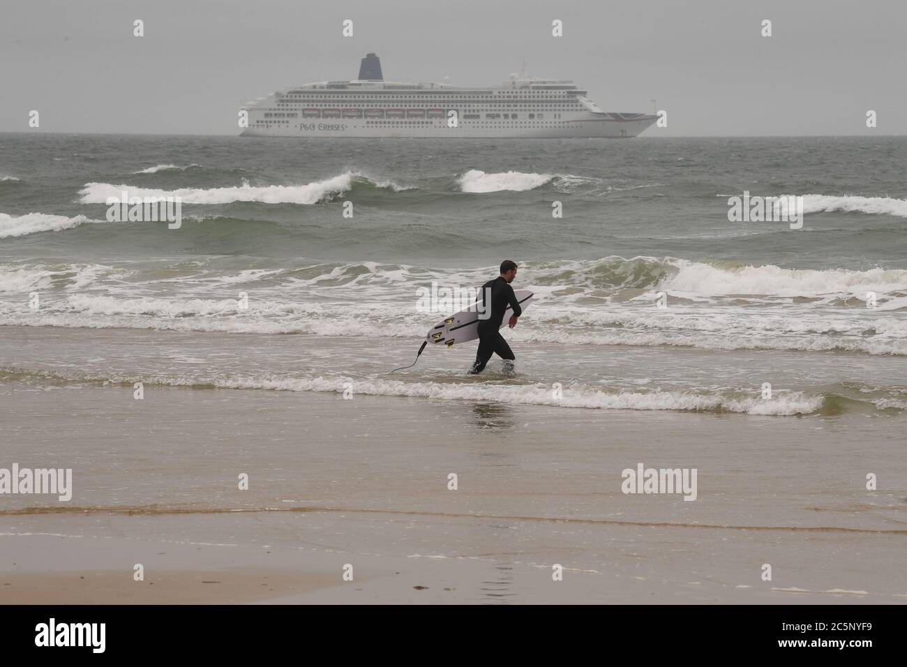 Surfeur sur la plage de Bournemouth malgré la pluie et la bruine que l'on attend dans une grande partie du pays. Banque D'Images