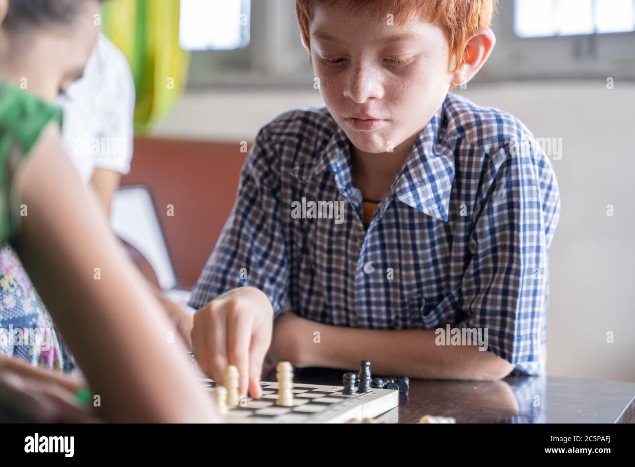 Joueur d'échecs sérieux de pensée et de mouvement de pièce à la maison - concept de la concentration de jeu d'enfant pendant le développement précoce, à la maison jeux éducatifs pour Banque D'Images