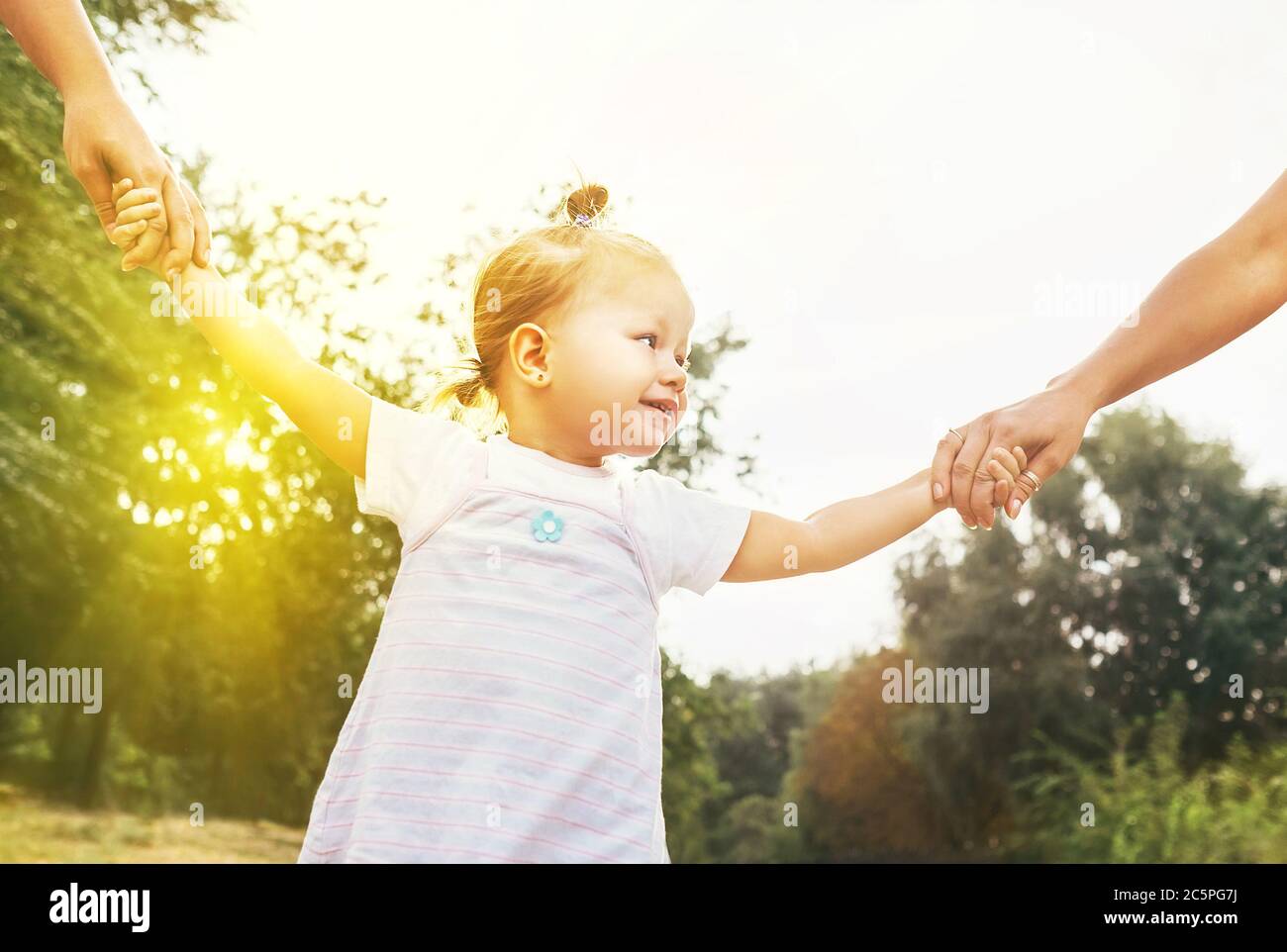 Petite fille mignon prendre les mains avec ses parents gens. Concept de marche avec enfants. Banque D'Images