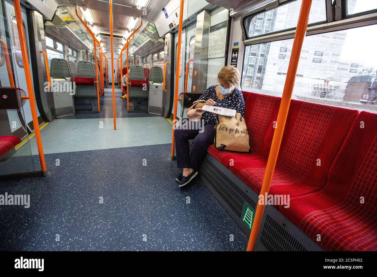 Une dame s'assoit à lire son journal tout en portant un masque facial obligatoire lors d'un voyage à bord d'une voiture vide sur les trains du sud-ouest du Royaume-Uni Banque D'Images