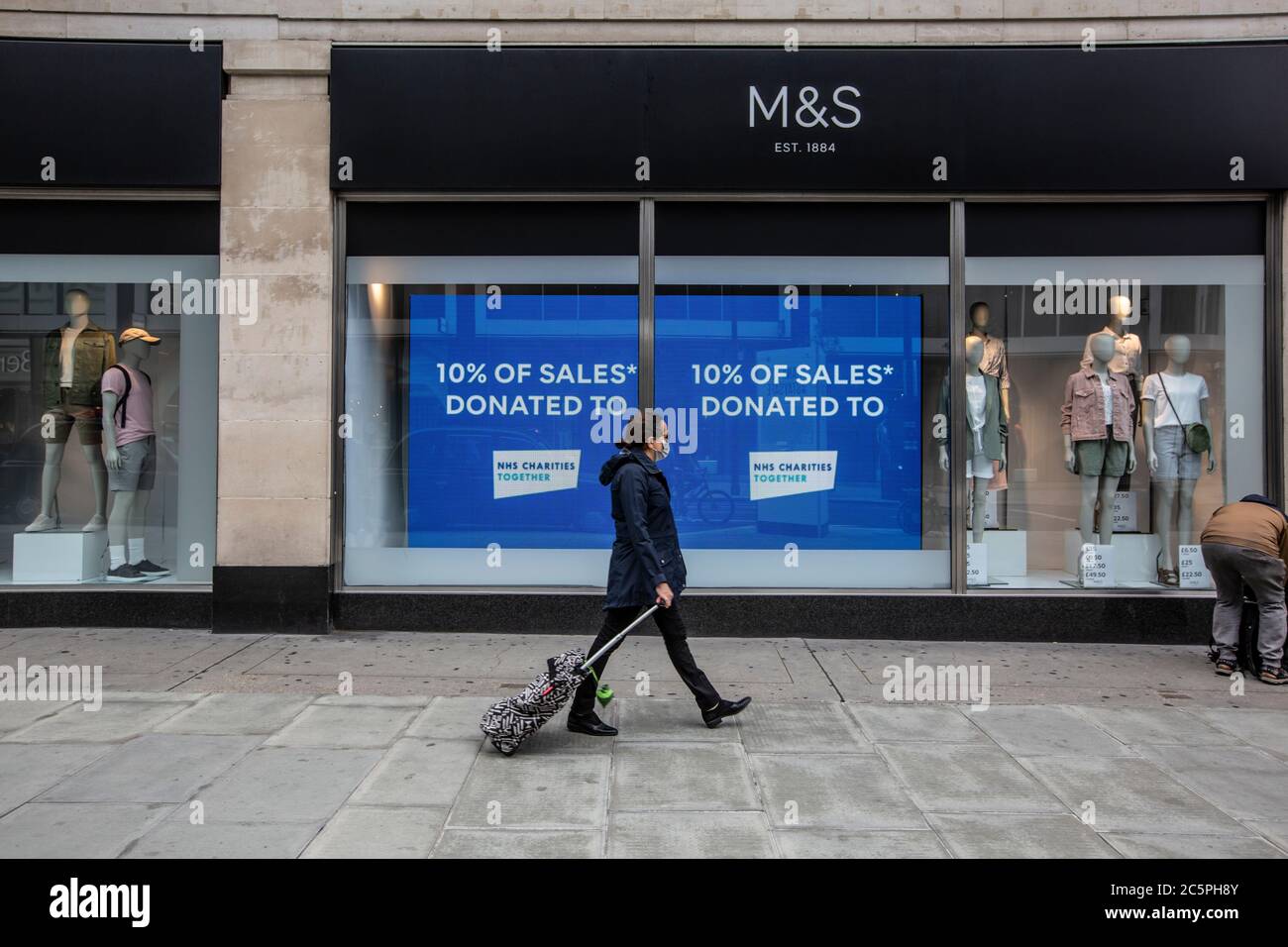 Un piéton qui porte un masque facial passe devant le grand magasin Marks & Spicers d'Oxford Street, West End, Central London, Angleterre, Royaume-Uni Banque D'Images