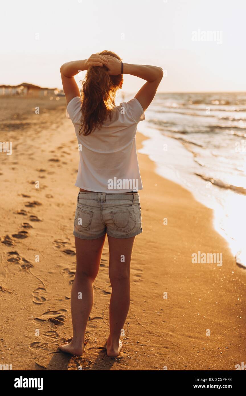 Fille regarde le coucher du soleil sur la mer. Été Banque D'Images