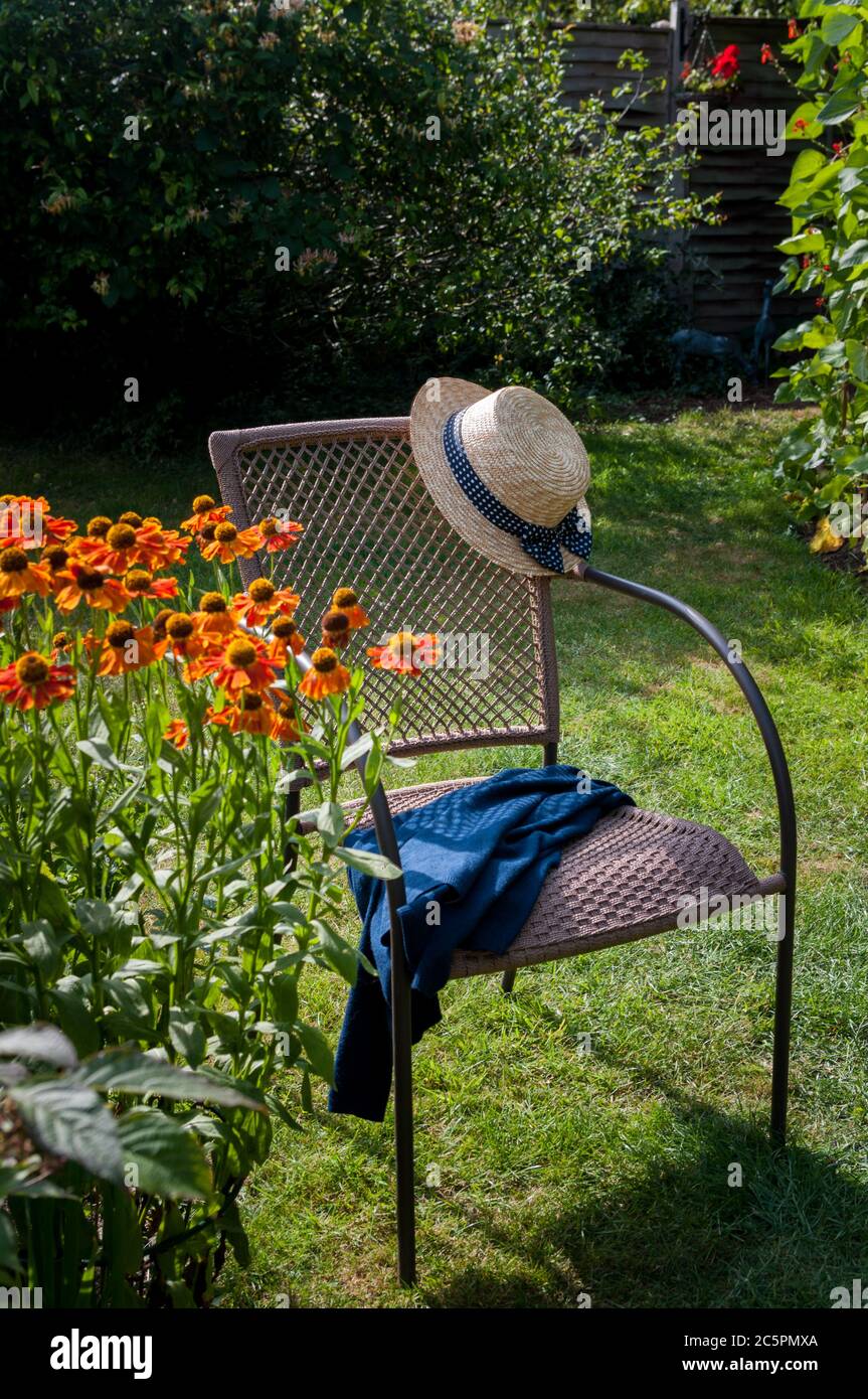 Chapeau de paille style plaisancier d'été avec ruban bleu sur chaise de  jardin extérieur avec veste ou gilet bleu, jour d'été ensoleillé, héliums  en premier plan, ronne Photo Stock - Alamy