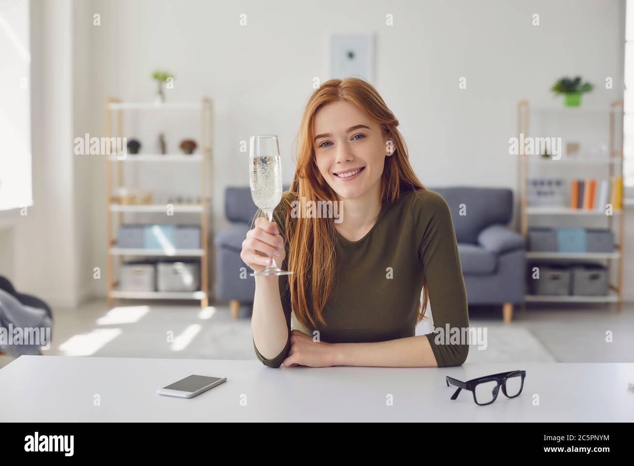 Femme souriante avec une coupe de champagne dans le salon Banque D'Images