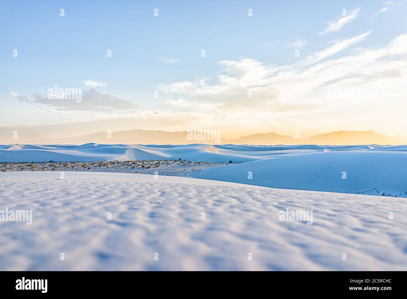Dunes de sable blanc parc national monument collines de sable de gypse au Nouveau-Mexique avec la silhouette des montagnes d'orgue à l'horizon pendant le coucher de soleil jaune coloré Banque D'Images