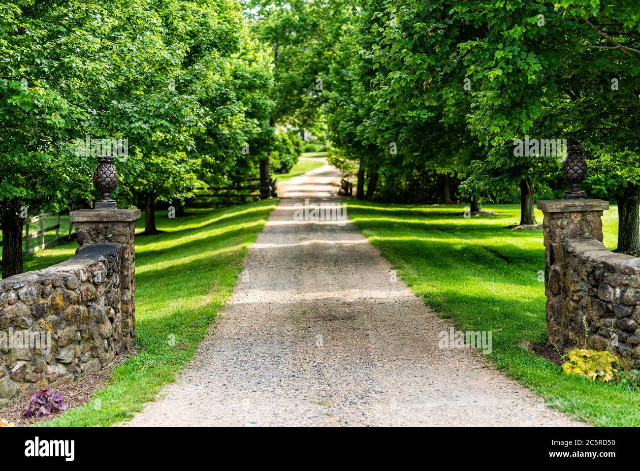 Entrée ouverte et fermée avec allée dans la campagne rurale dans le domaine de Virginie avec clôture en pierre et chemin de terre en gravier rue avec arbres verts luxuriants en s. Banque D'Images
