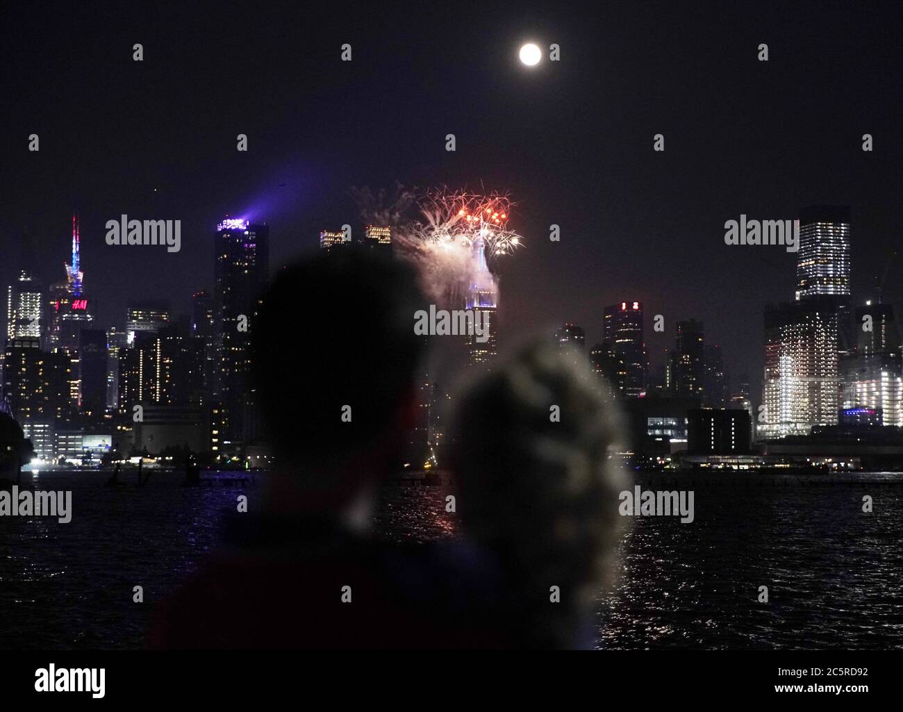 Weehawken, États-Unis. 04e juillet 2020. Un homme et sa fille regardent des feux d'artifice illuminant l'Empire State Building et les gratte-ciel de Manhattan pour le spectacle annuel de feux d'artifice du 4 juillet de Macy, le jour de l'indépendance, le samedi 4 juillet 2020 à Weehawken, New Jersey. Macy's a mis sur le dernier de ce qui était plusieurs petits feux d'artifice non annoncés pour les vacances du 4 juillet. La ville de New York se prépare à entrer dans la phase 3 d'un plan de réouverture en quatre parties le 6 juillet après avoir été fermée pendant près de 4 mois en raison de la COVID-19. Photo de John Angelillo/UPI crédit: UPI/Alay Live News Banque D'Images
