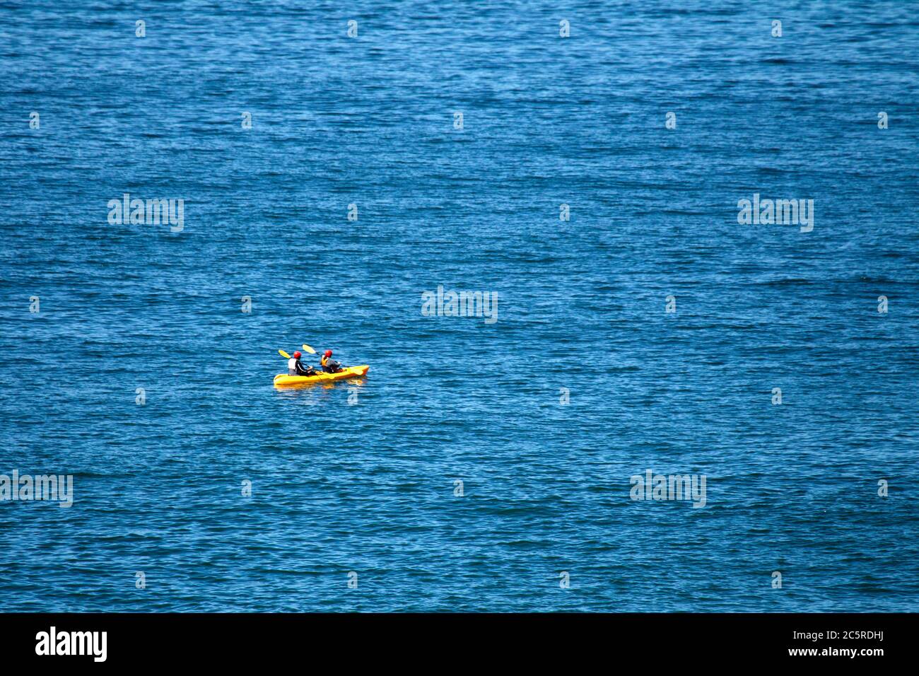 Deux personnes portant un casque rouge en kayak de mer jaune Banque D'Images