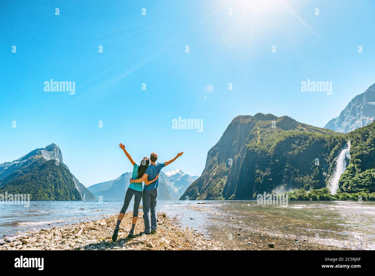 Couple en plein air heureux avec les bras débordés dans Milford Sound New La Zélande dans la nature en profitant de la vie active de randonnée en plein air à Milford Nouveau son Banque D'Images