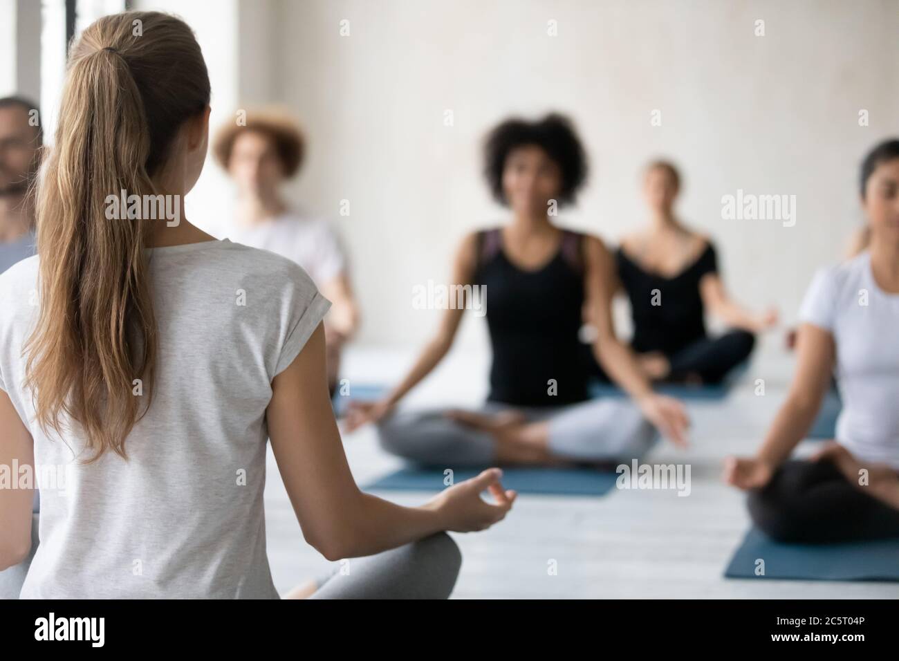 Vue arrière jeune instructeur professionnel donnant cours de yoga. Banque D'Images