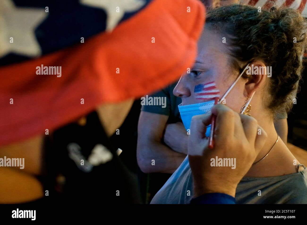Un homme israélien vêtu de la tenue de l'oncle Sam peint le drapeau américain sur le visage d'une femme lors de la célébration du jour de l'indépendance des États-Unis le 4 juillet à Jérusalem Israël. Banque D'Images