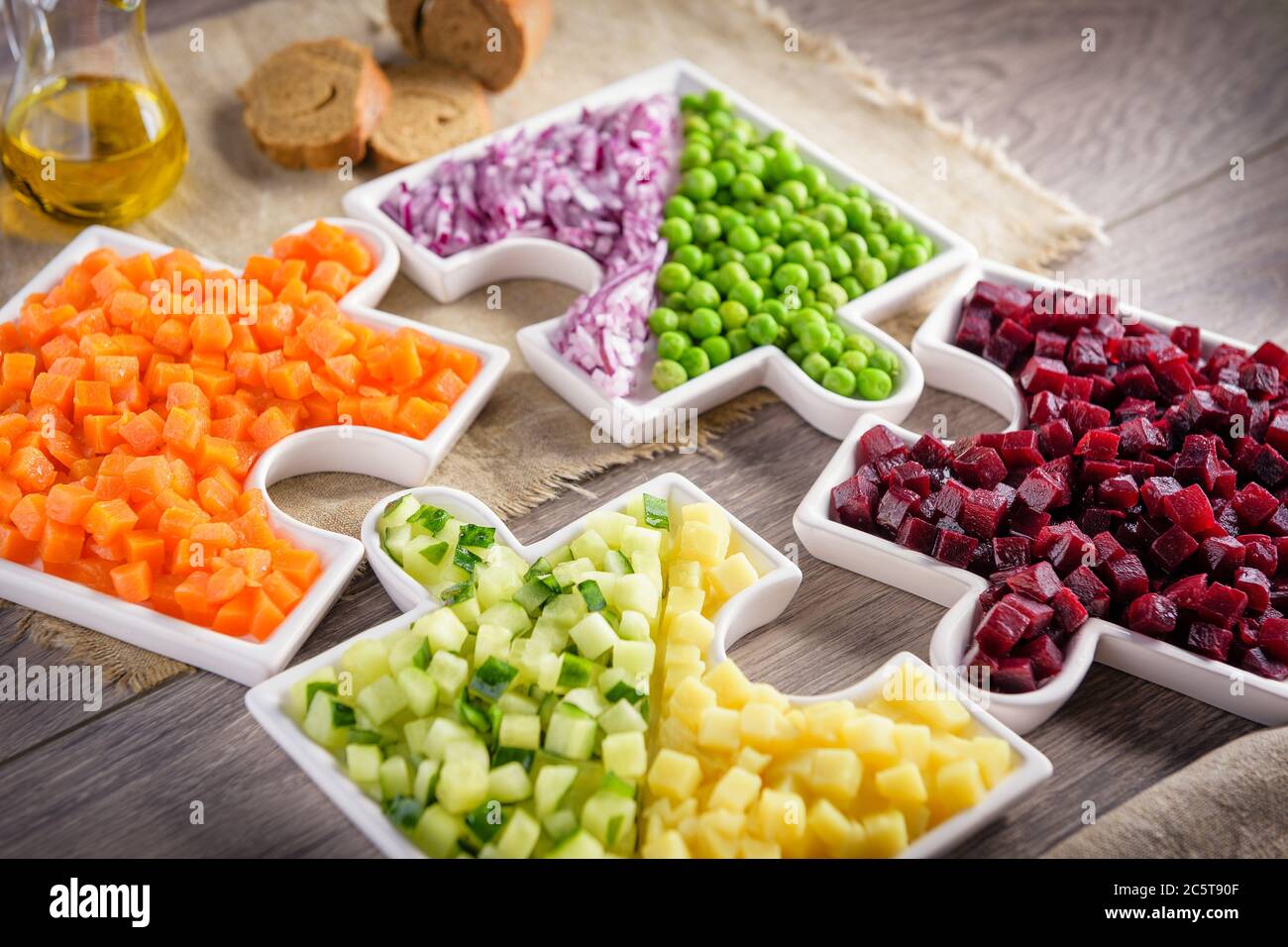 Légumes crus les carottes, les pois, les oignons, le concombre, les pommes de terre, les betteraves coupées en cubes sont sur des assiettes qui sont recueillies dans des puzzles. Banque D'Images