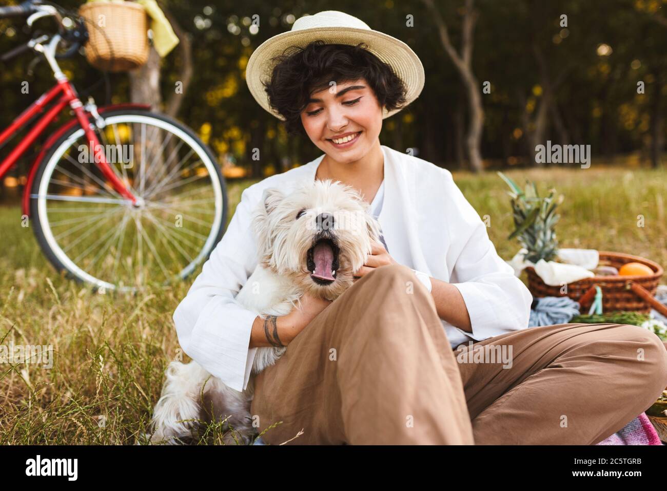 Jolie fille en chapeau tenant un chien mignon passer du temps sur pi Banque D'Images