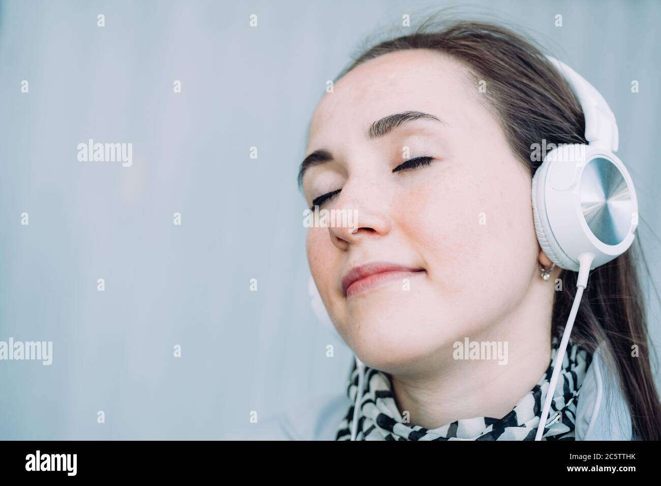 Une jeune fille de race blanche sourit et écoute de la musique avec les yeux fermés Banque D'Images