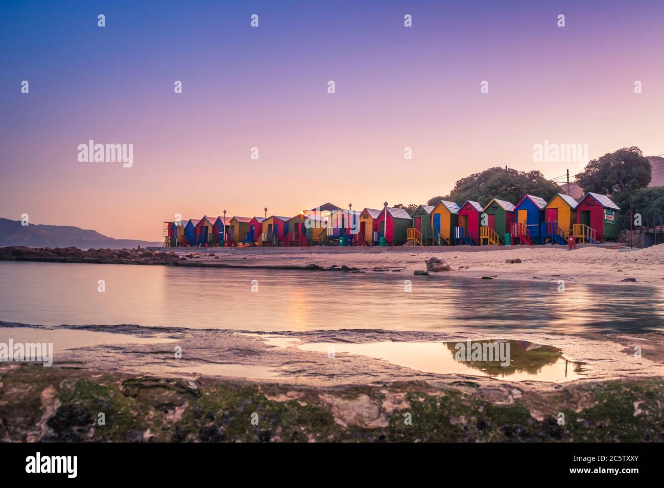 Vue sur le magnifique coucher de soleil sur False Bay de Kalkbay avec des petites maisons colorées sur la plage, avec des montagnes en arrière-plan, le Cap, Sud Banque D'Images