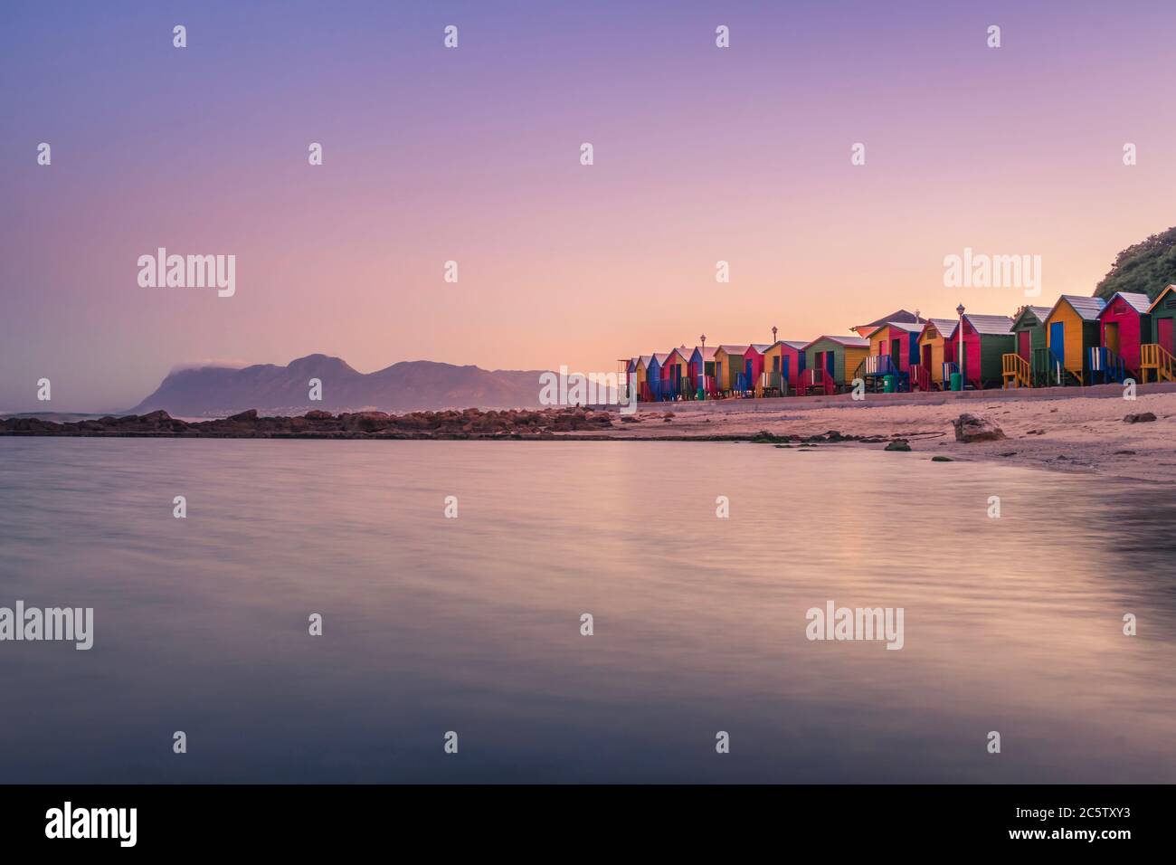Vue sur le magnifique coucher de soleil sur False Bay de Kalkbay avec des petites maisons colorées sur la plage, avec des montagnes en arrière-plan, le Cap, Sud Banque D'Images