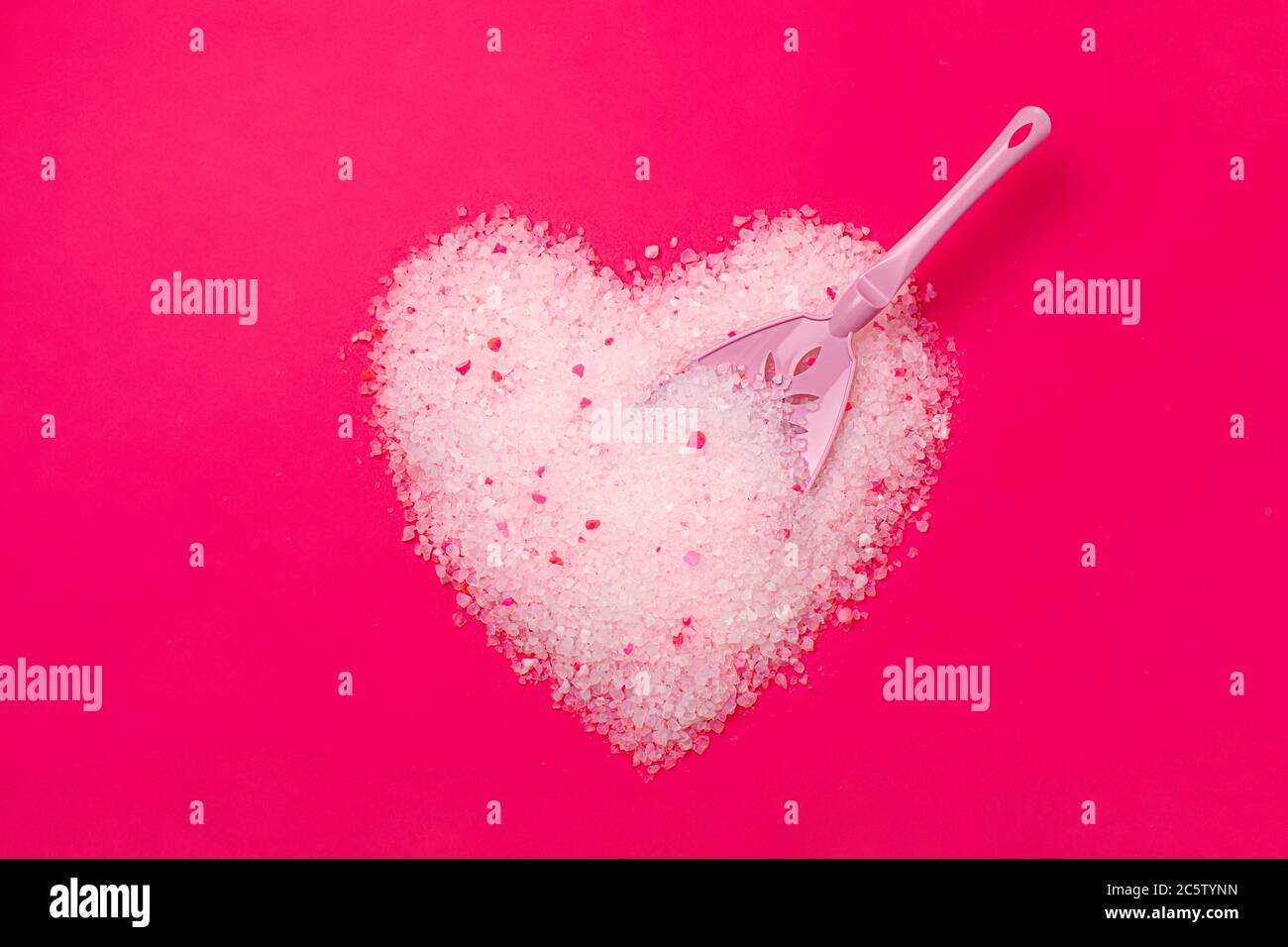 Litière pour chats, fond rose vif en forme de coeur avec une spatule pour le nettoyage du poop. Concept pour les étiquettes, emballage publicité de l'amour de l'hôte animal Banque D'Images