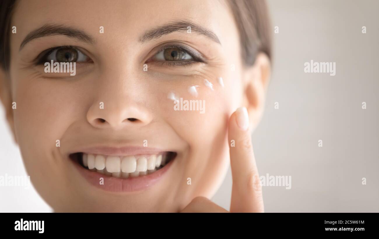 Gros plan sourire belle femme appliquant de la crème hydratante pour le visage Banque D'Images
