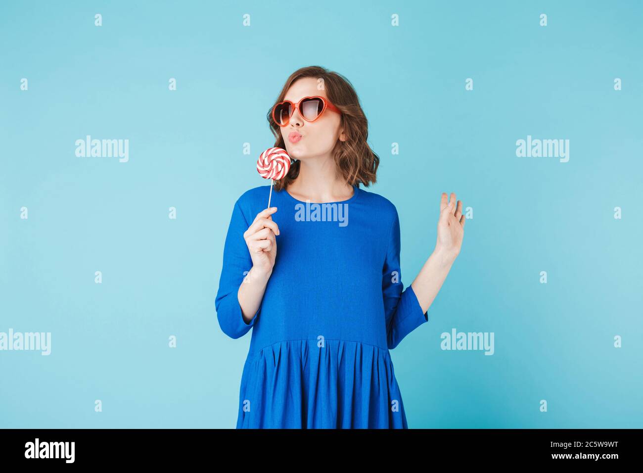 Photo de jolie dame en coeur lunettes de soleil et robe debout avec bonbon de  Lollipop à la main sur fond bleu Photo Stock - Alamy