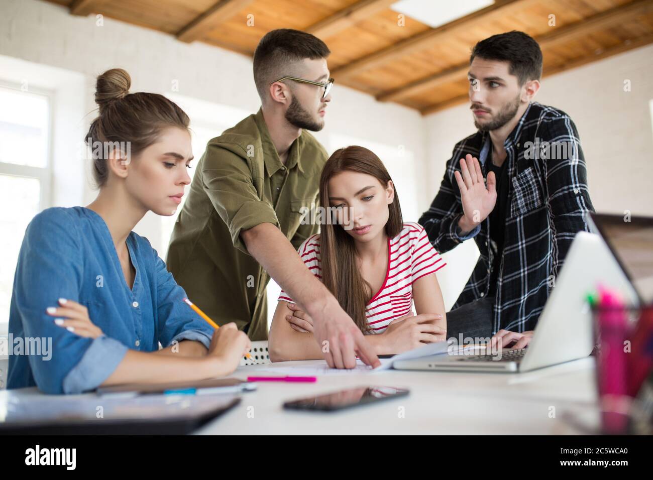 Groupe d'hommes et de femmes d'affaires travaillant avec discernement avec des croquis tout en passant du temps au travail. Les jeunes discutent émotionnellement du nouveau projet Banque D'Images