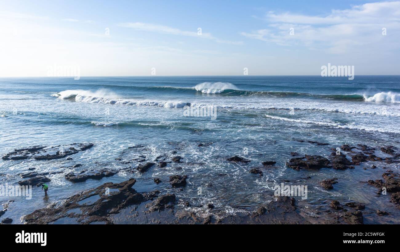 Vagues d'eau bleue sur l'océan qui se brisent sur des bancs de sable peu profonds surplombant la plage, littoral panoramique horizon paysage. Banque D'Images