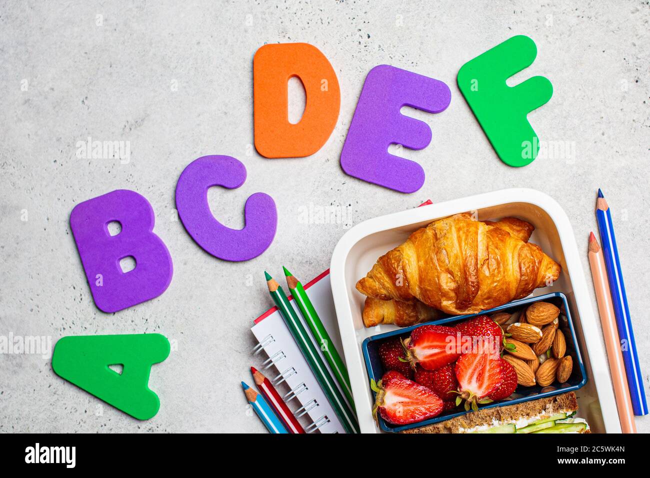 Concept de retour à l'école. Boîte à lunch avec sandwich, croissants et en-cas pour l'école. Fond de l'école avec l'inscription. Banque D'Images