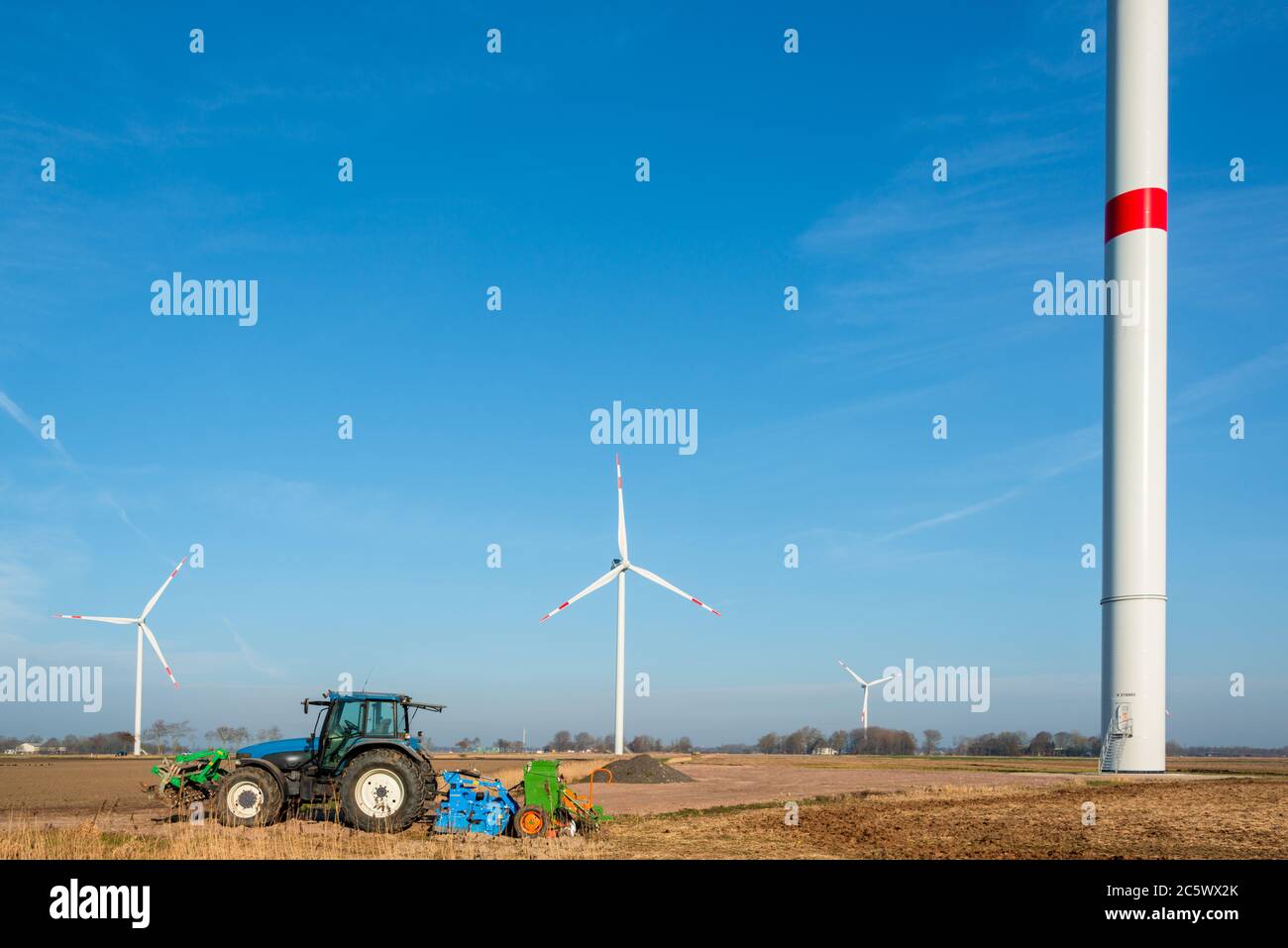 Bauer mit seinem Traktor in Dithmarschen Schleswig-Holstein mitten in einem riesigen Windpark Banque D'Images