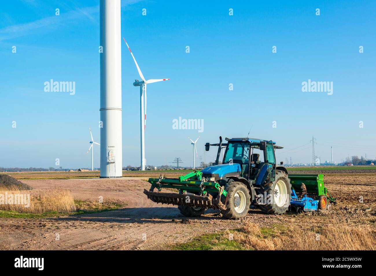 Bauer mit seinem Traktor in Dithmarschen Schleswig-Holstein mitten in einem riesigen Windpark Banque D'Images
