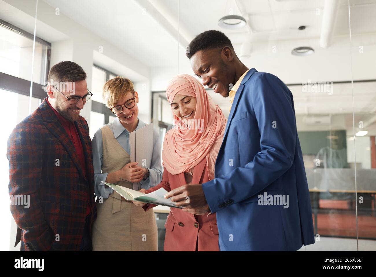 Portrait de l'équipe multiethnique contemporaine discutant de projet d'affaires au bureau, concentrez-vous sur une femme d'affaires musulmane souriante parlant à des collègues Banque D'Images