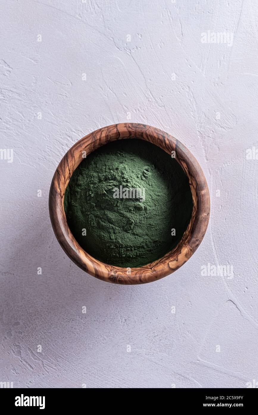 Poudre de chlorella ou de spiruline verte naturelle dans un bol rond d'olivier brun en bois, directement au-dessus. Concept de nourriture saine et de régime. W Banque D'Images