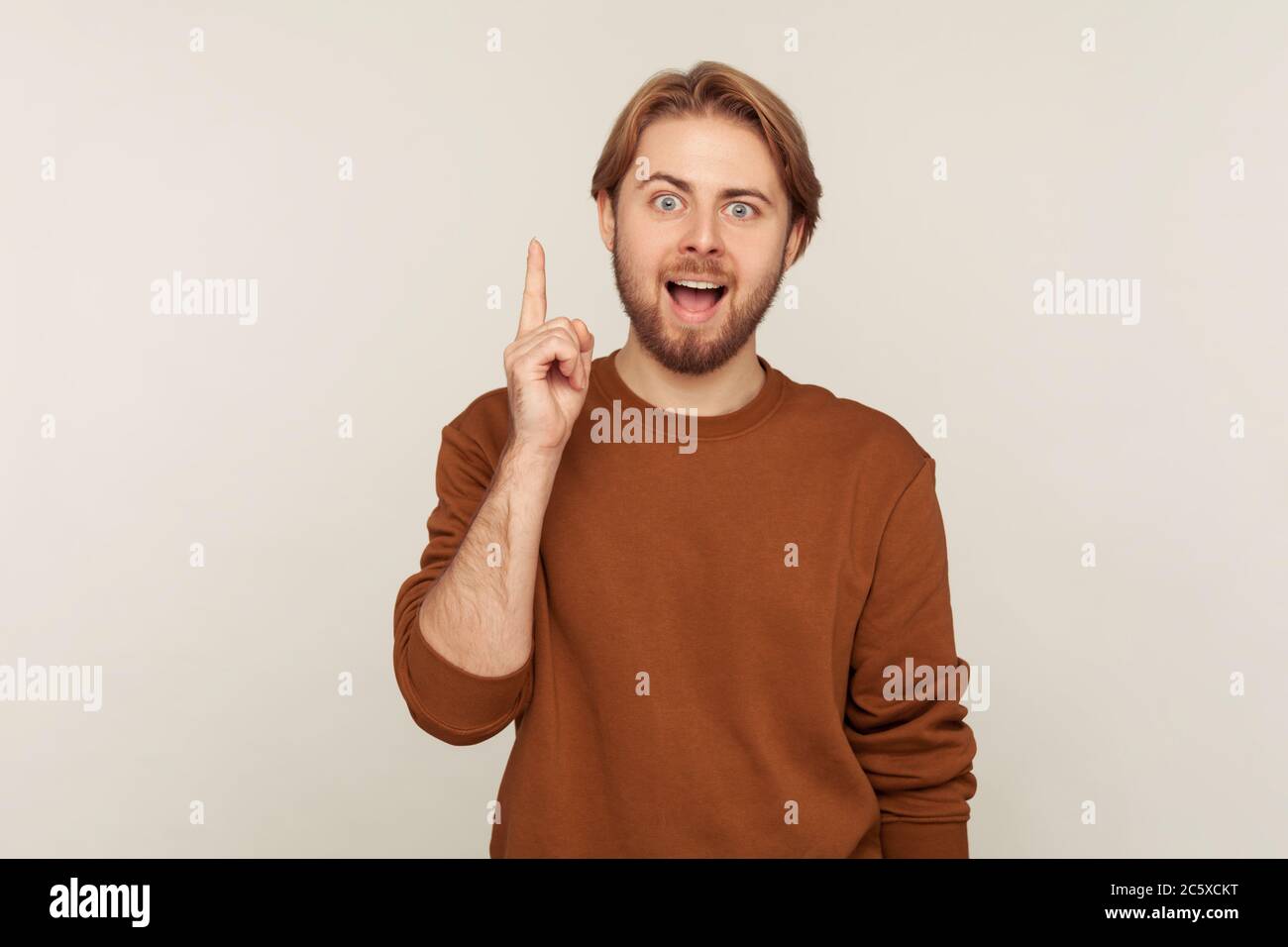 Eureka ! Je sais répondre! Portrait d'un homme avec une barbe en sweat-shirt levant le doigt ayant une bonne idée, regardant surpris par soudainement inventé la solution intelligente Banque D'Images
